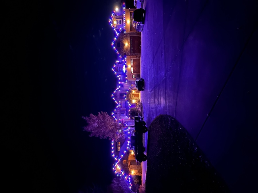 Large estate home lit in red, white and blue roofline lights at night