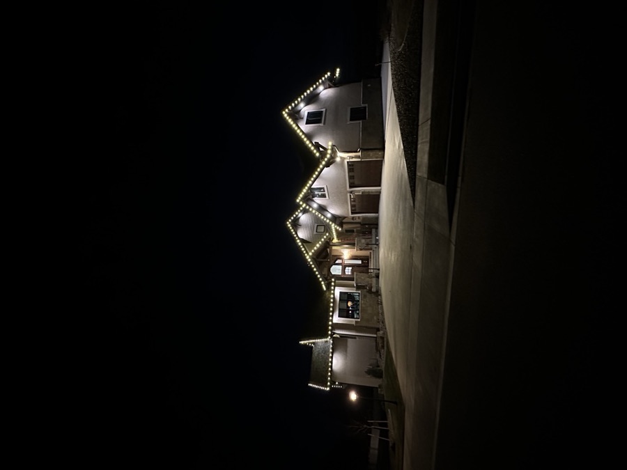 Large stucco home with crisp warm white lights following every roofline and peak